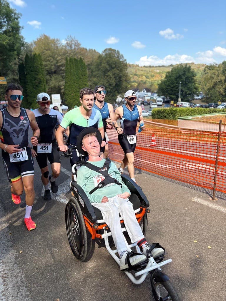 L’équipe pousse Val en fauteuil de course pendant le triathlon